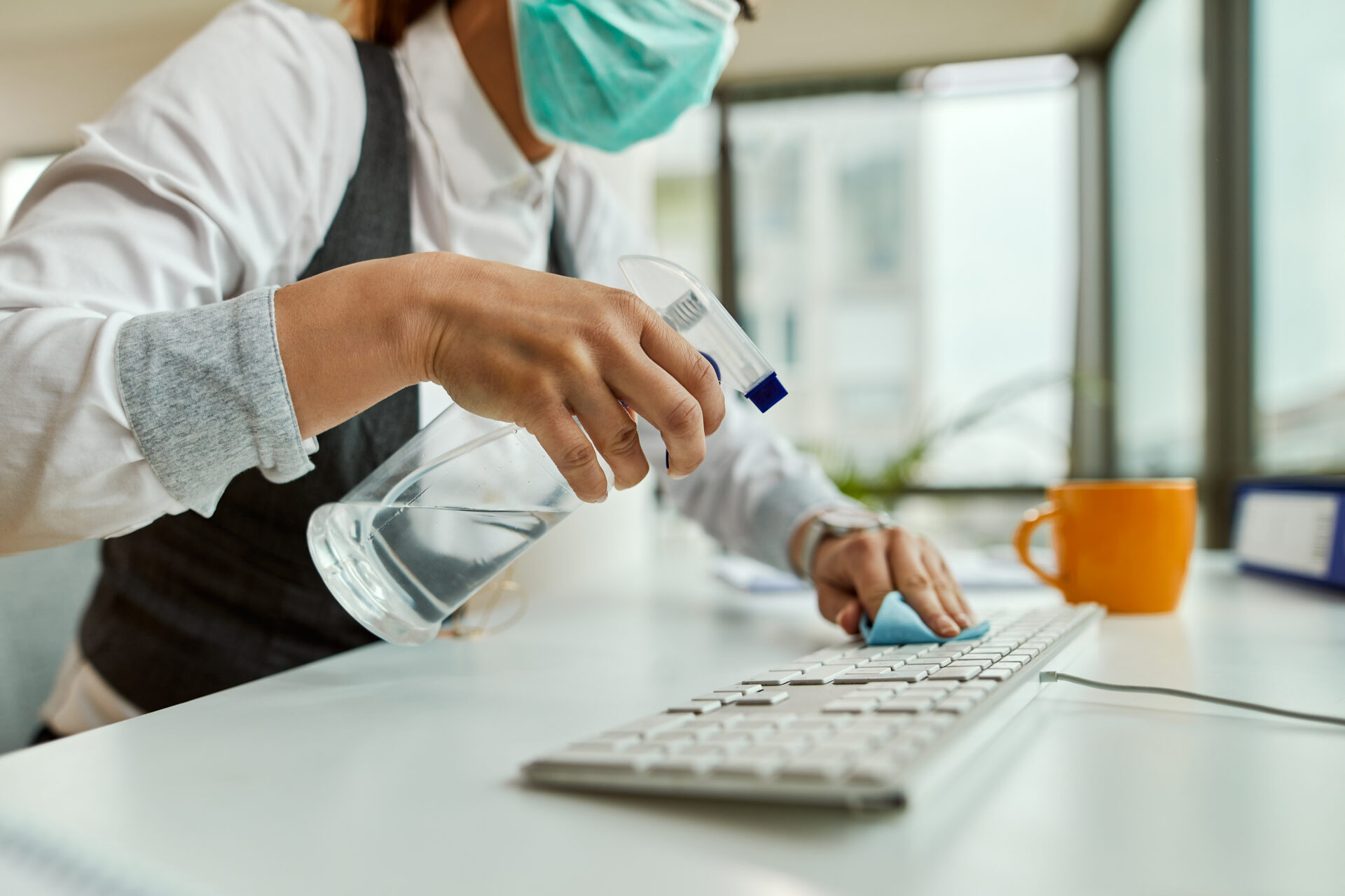 man cleaning mac keyboard with disinfectant spray