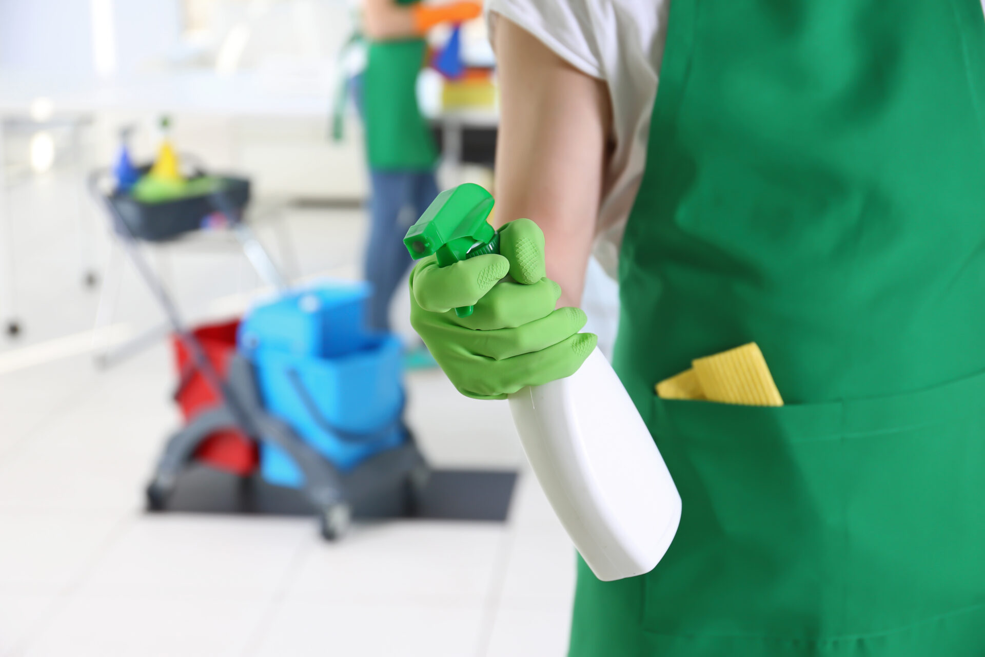 Woman holding cleaning spray bottle with cleaning gloves on