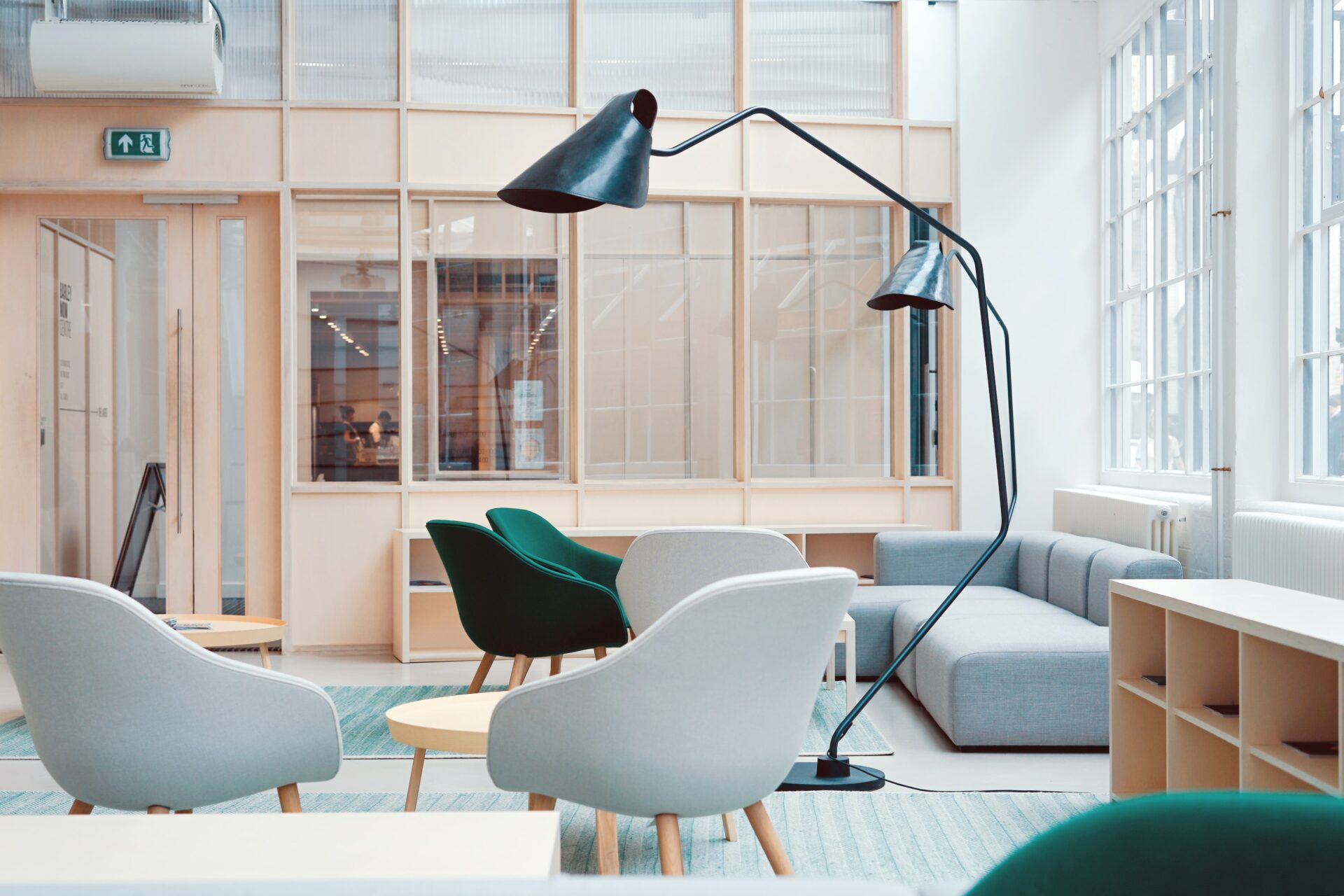 Clean, bright hygienic office space featuring a grey sectional, green and white chairs and a unique black lamp.