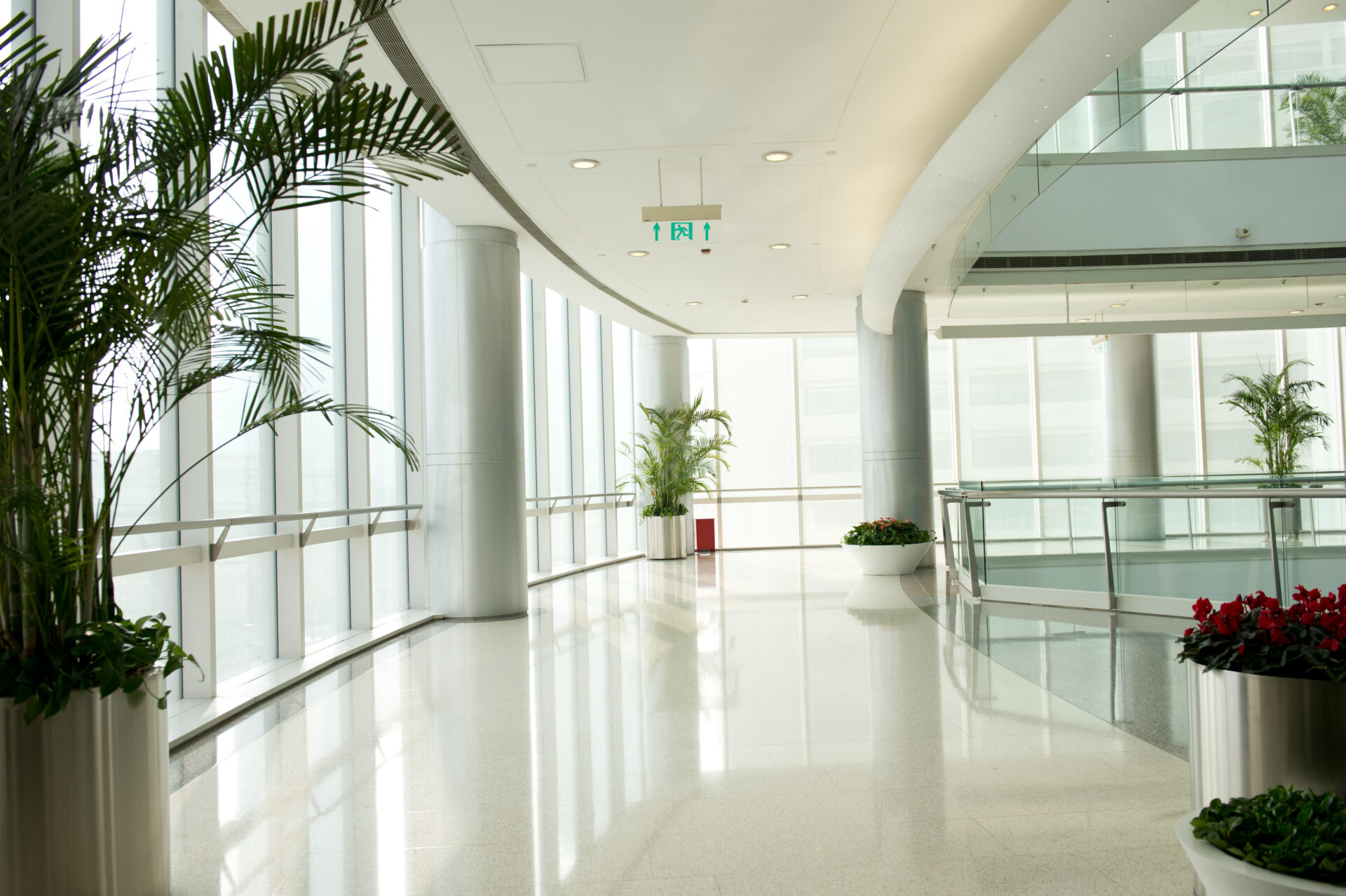 Clean, minimalistic style corridor in a modern and bright office building, showcasing mirror-shined tile flooring.